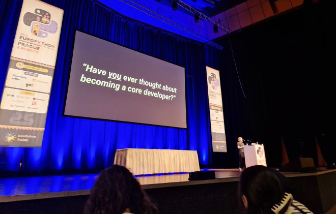 Savannah Bailey presenting the keynote with a slide reading 'Have you ever thought about becoming a core developer?'