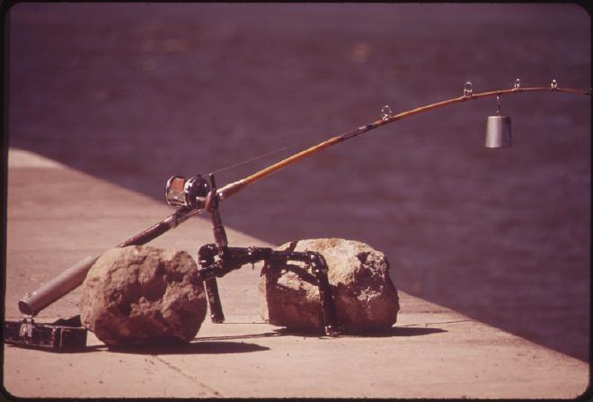 A fishing rod with a bell on it propped up over water