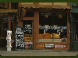 1942 store front of Grand Grocery Co. with many signs outside and lots of potatoes, oranges and grapefruit in the window. There are signs for Union Leader, Pepsi Cola, 7up, Beech Nut, Chew Copenhagen ('It's a pleasure') and Model Smoking Tobacco ('Did you say 10c?').