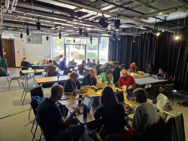 Another roomful of people working at laptops around tables
